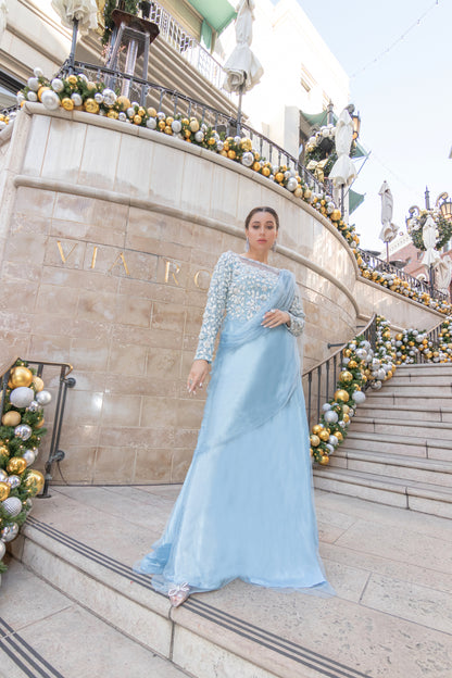 "Icy blue net saree: adorned blouse, stones, beads. Timeless grace, glamorous allure."